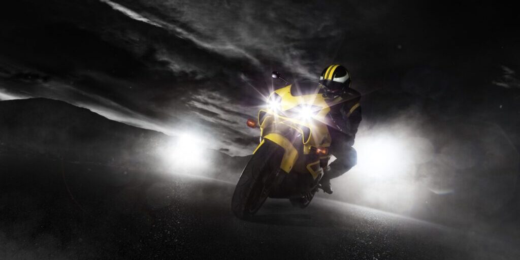 Motorcycle with HELLA X-Treme Series LED Driving Lights in white mode, IP69K, auxiliary high-beam for off-road adventure.