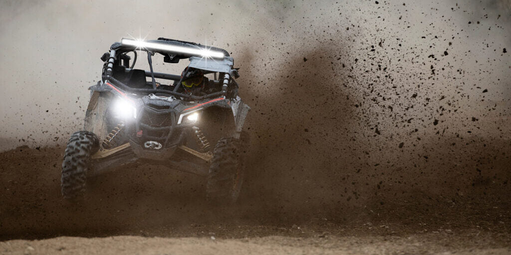 UTV with HELLA X-Treme Series LED Driving Lights in white mode, IP69K, roof rack mounted, auxiliary high-beam, X-shape position light, off-road action.