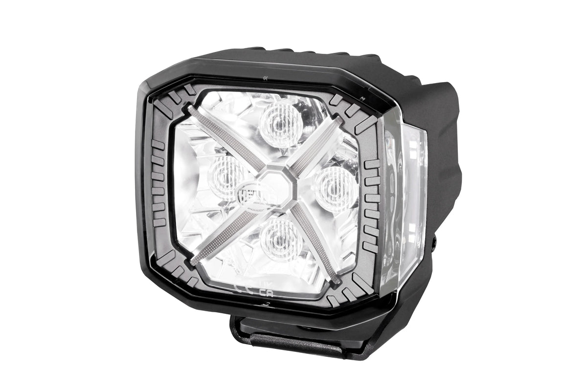 HELLA X-Treme Series LED Driving Light in white mode, showing X-shape position light, IP69K-rated rugged aluminum housing, auxiliary high-beam, off-road use.