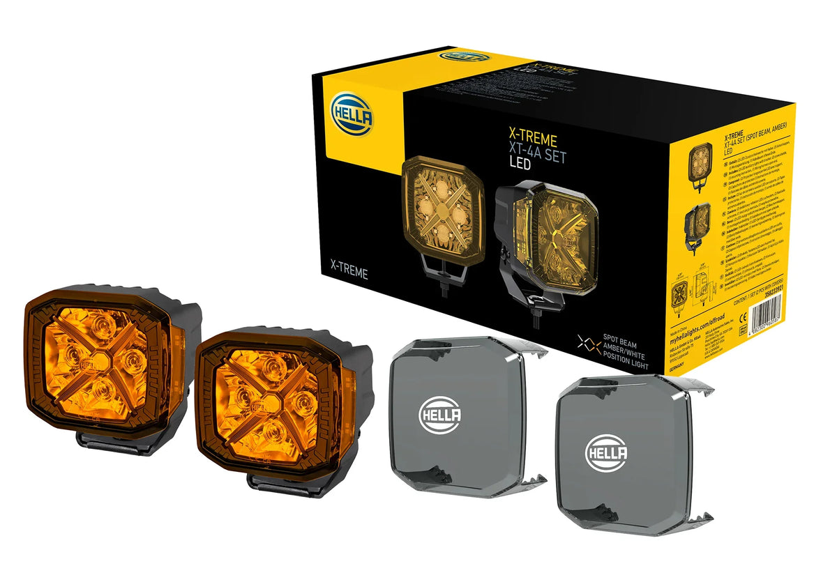HELLA X-Treme Series LED Driving Lights in amber mode with X-shape position light, IP69K, auxiliary high-beam, rugged aluminum housing, off-road ready.